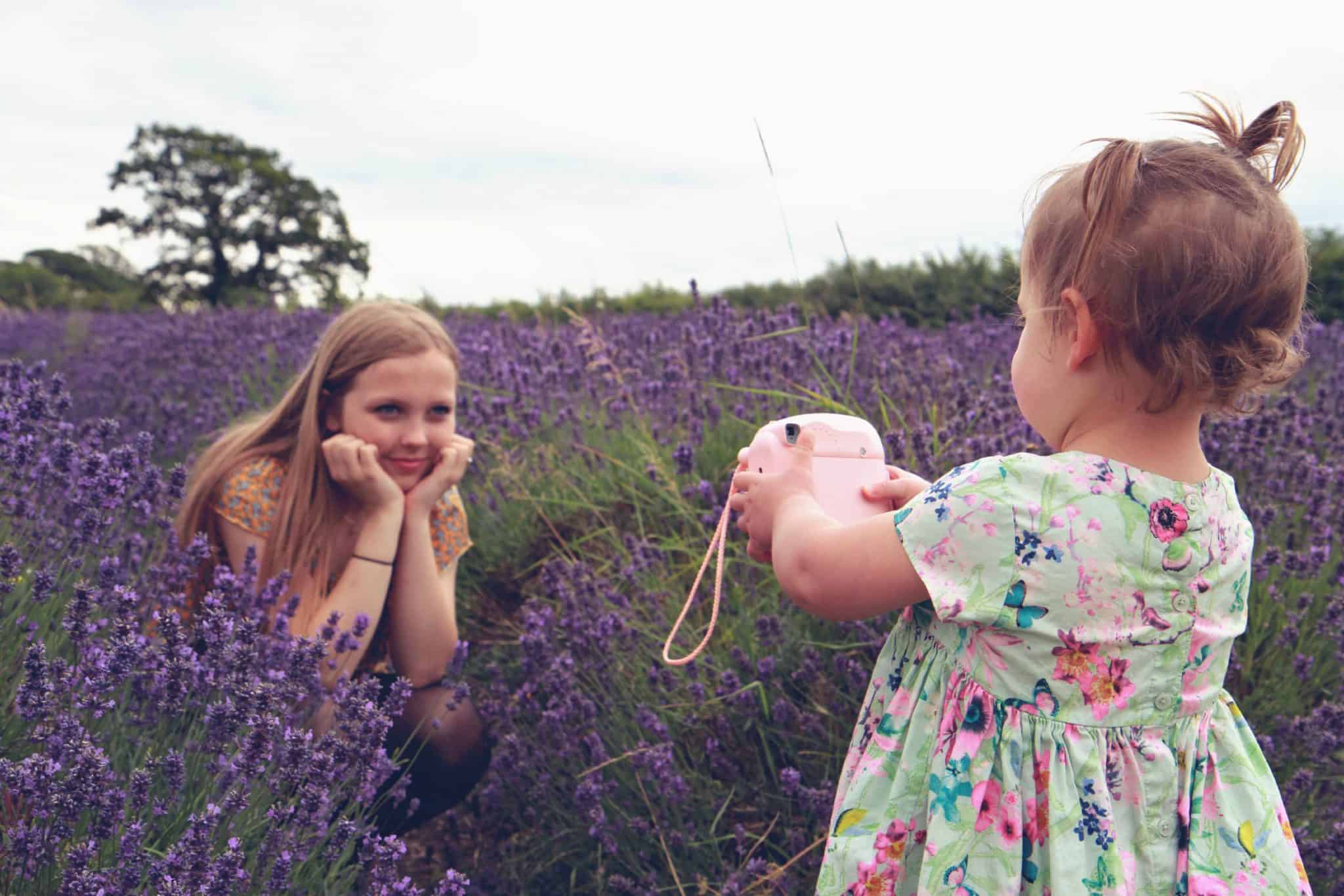two sisters playing with a polaroid camera in the middle of a lavender field