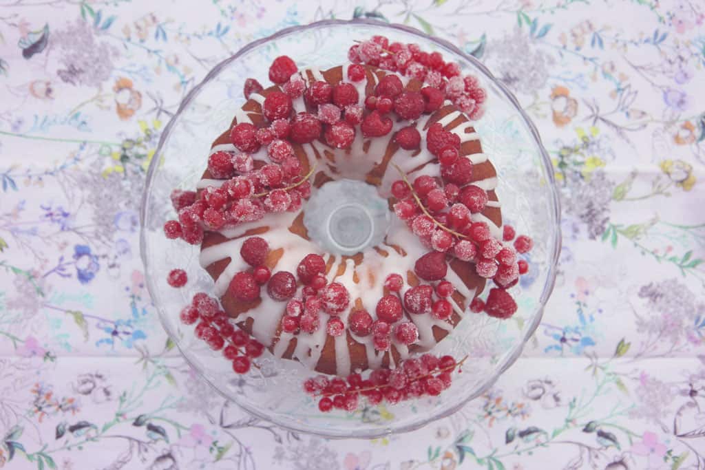 Lemon drizzle bundt cake decorated with raspberries and redcurrants