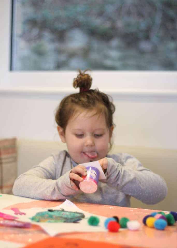 Little girl eating a pot of Petits Filous