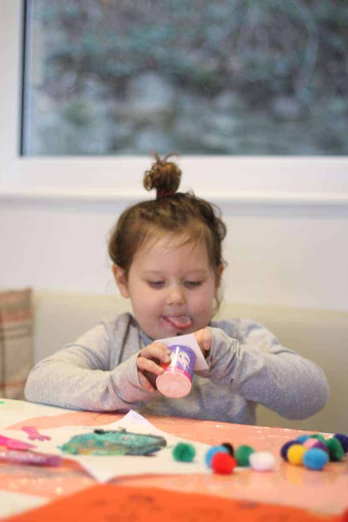 Little girl eating a pot of Petits Filous