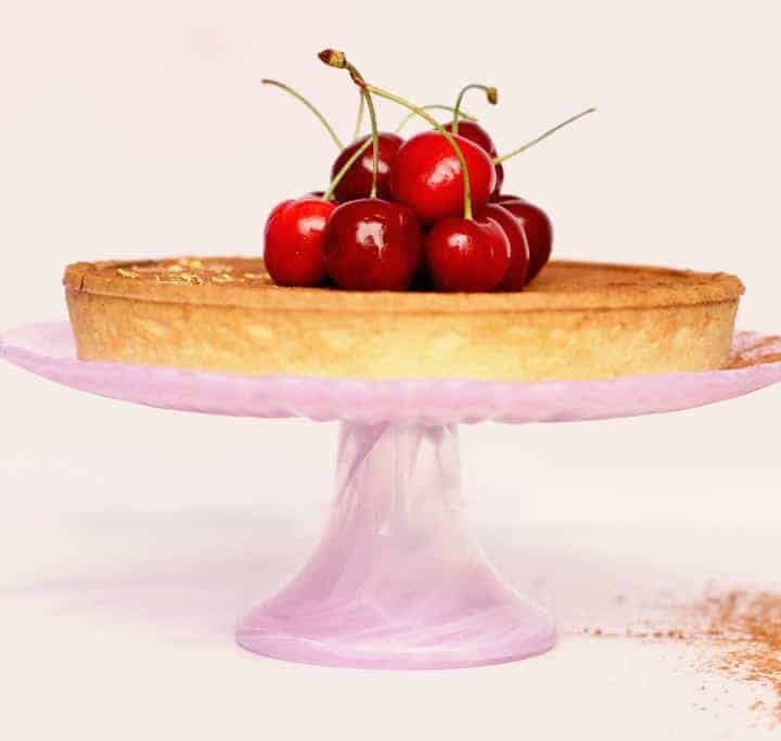 Side view of a salted caramel and chocolate tart with cherries on top