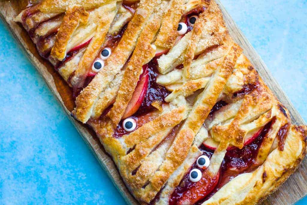 A mummy apple pie, spread with strawberry jam and 'bandages' made from puff pastry