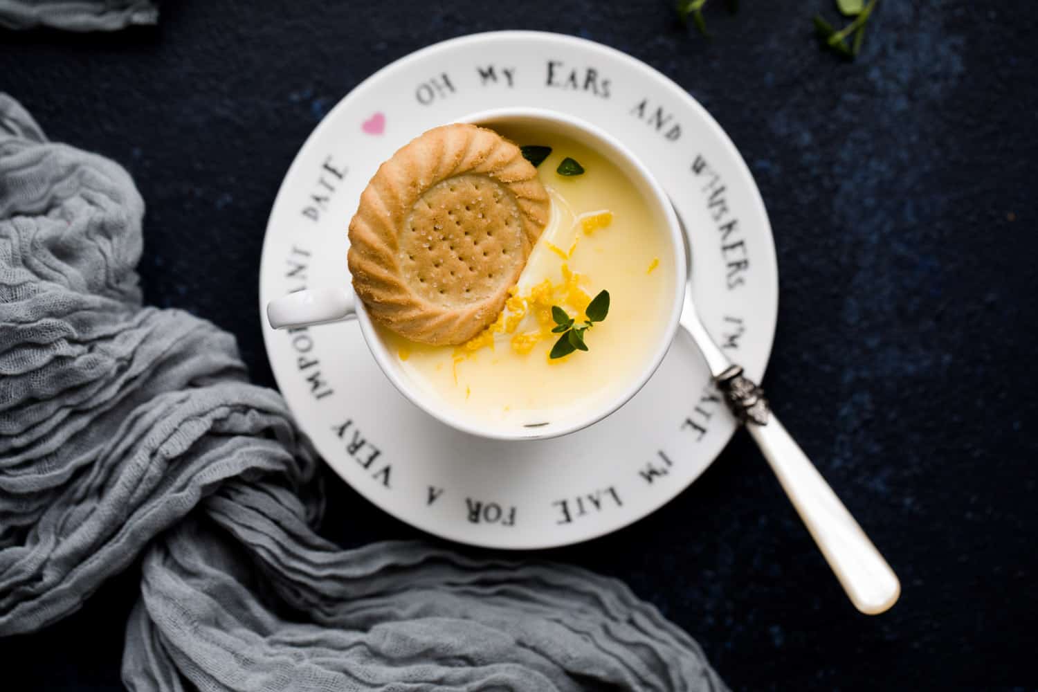 A lemon posset dessert in a teacup with a shortbread biscuit balanced on top