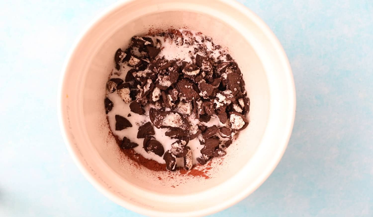 A mixing bowl with flour, sugar, cocoa powder and crushed Oreos