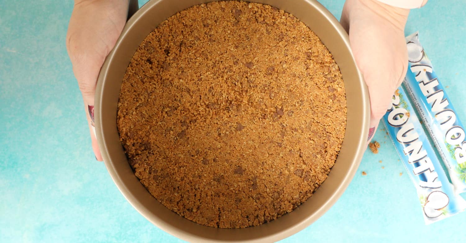 A round cake tin filled with a biscuit cheesecake base