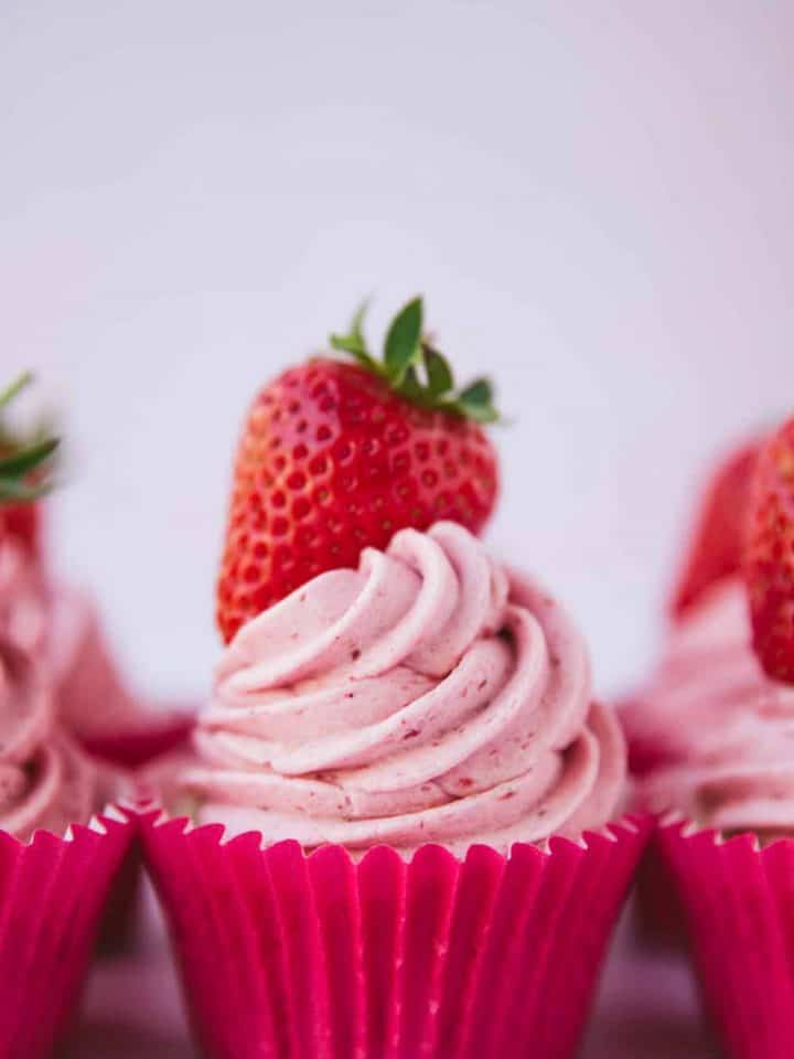A cupcake topped with a swirl of pink strawberry frosting