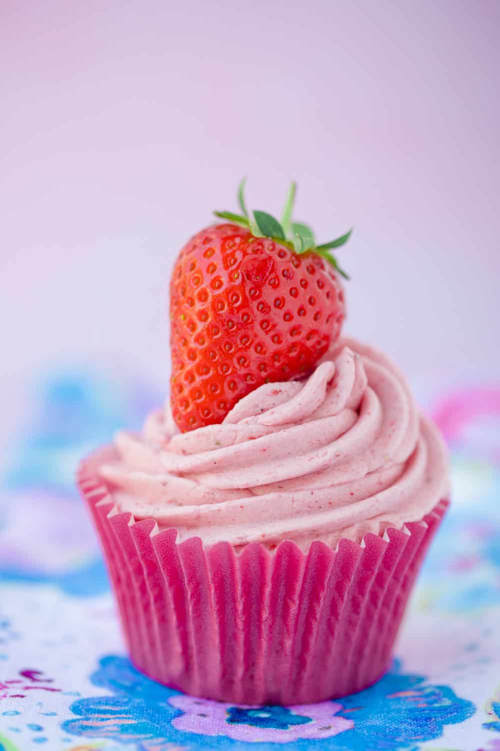 A cupcake topped with a swirl of pink strawberry frosting