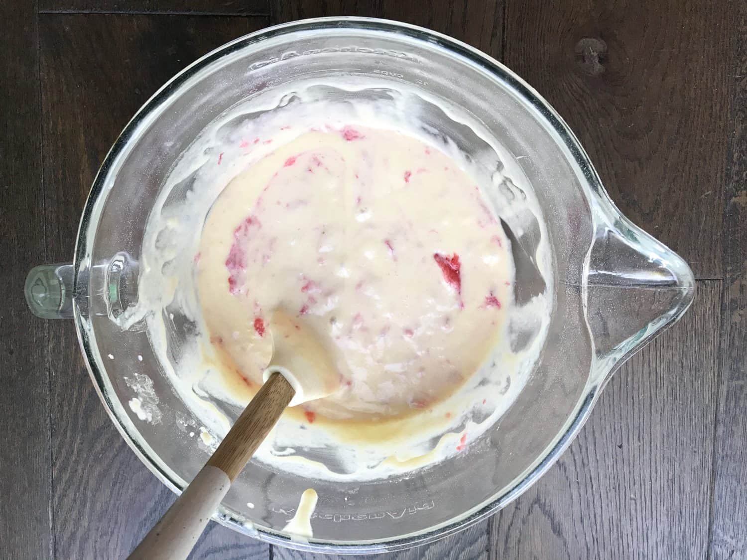 A mixing bowl filled with vanilla cupcake mixture and fresh strawberries