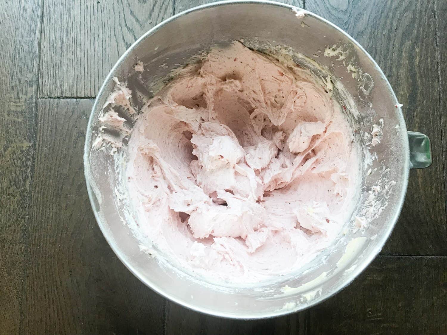A mixing bowl filled with strawberry buttercream