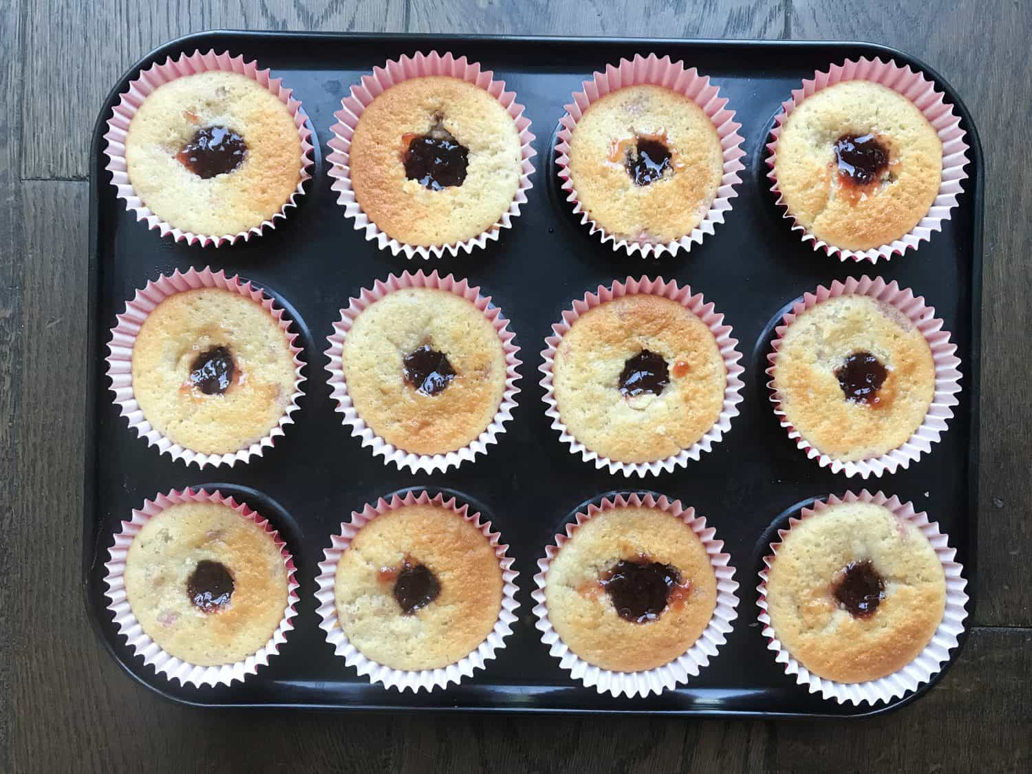 A baking tray of 12 cupcakes with the jam in the centres