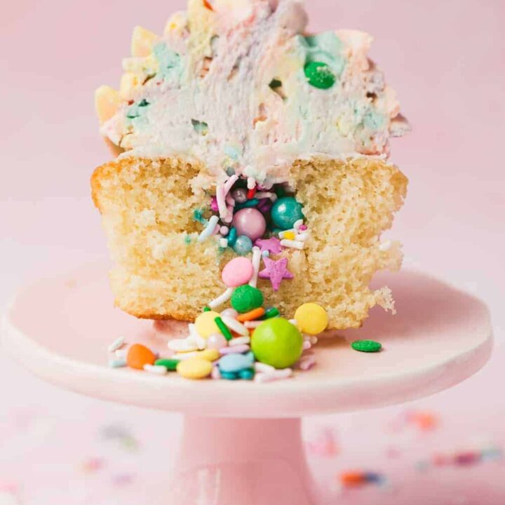 A cupcake cut in half with sprinkles cascading out from it