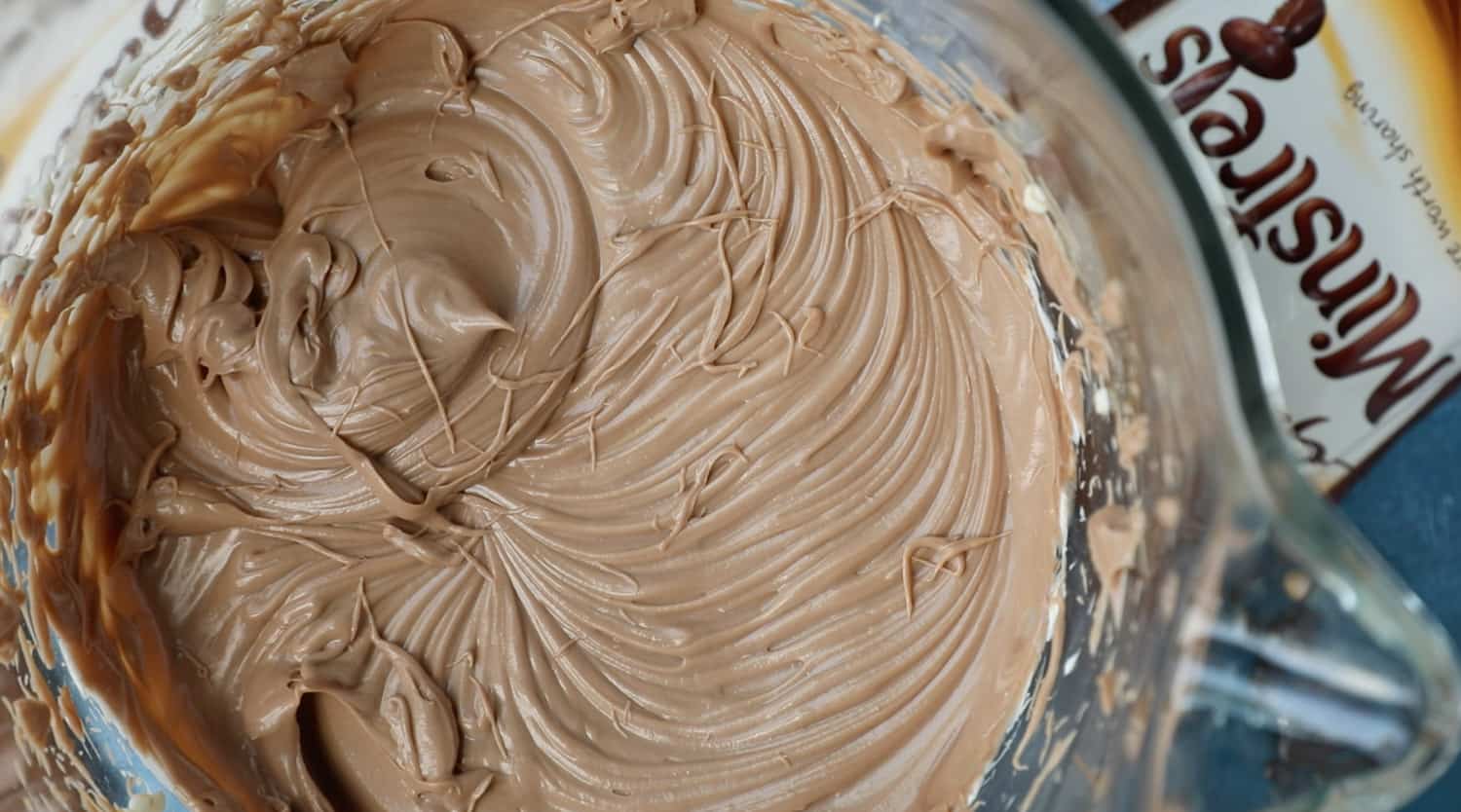 A mixing bowl with cream cheese, icing sugar and melted chocolate that has been mixed together. 