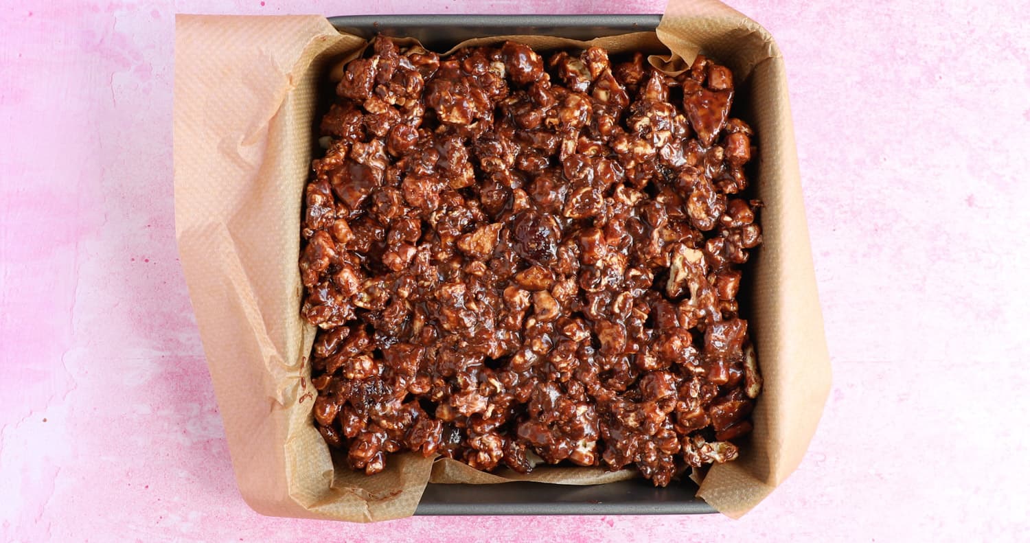 Popcorn rocky road mixture that has been pressed into a square baking tin.