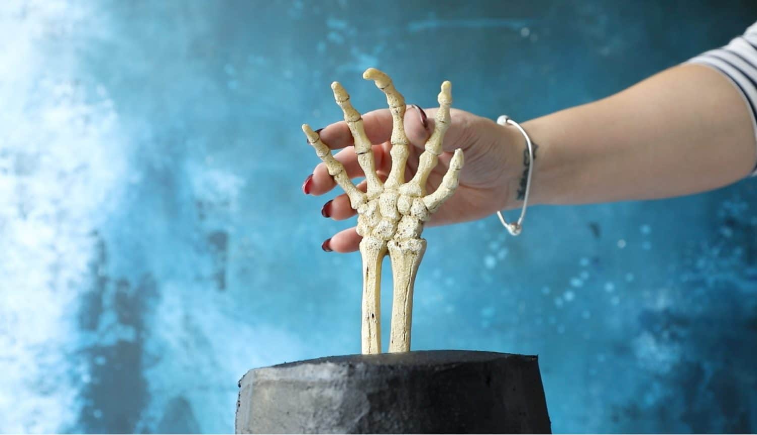 Pushing a skeleton hand into the top of a Halloween cake.
