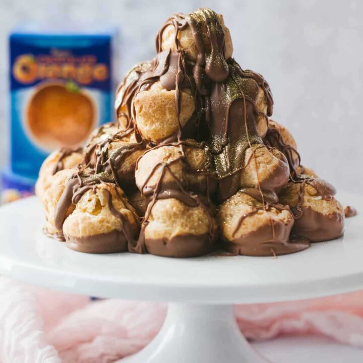 A profiterole tower covered in chocolate sauce.