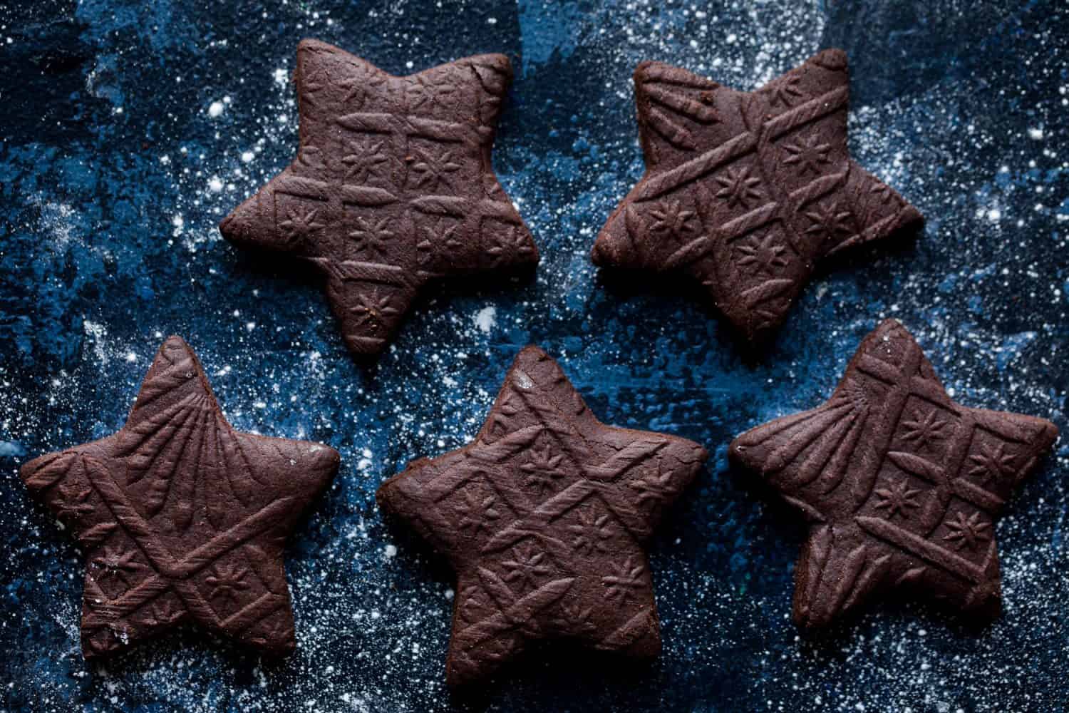 5 star shaped biscuits on a dark blue background that have been rolled with a pattern rolling pin. 