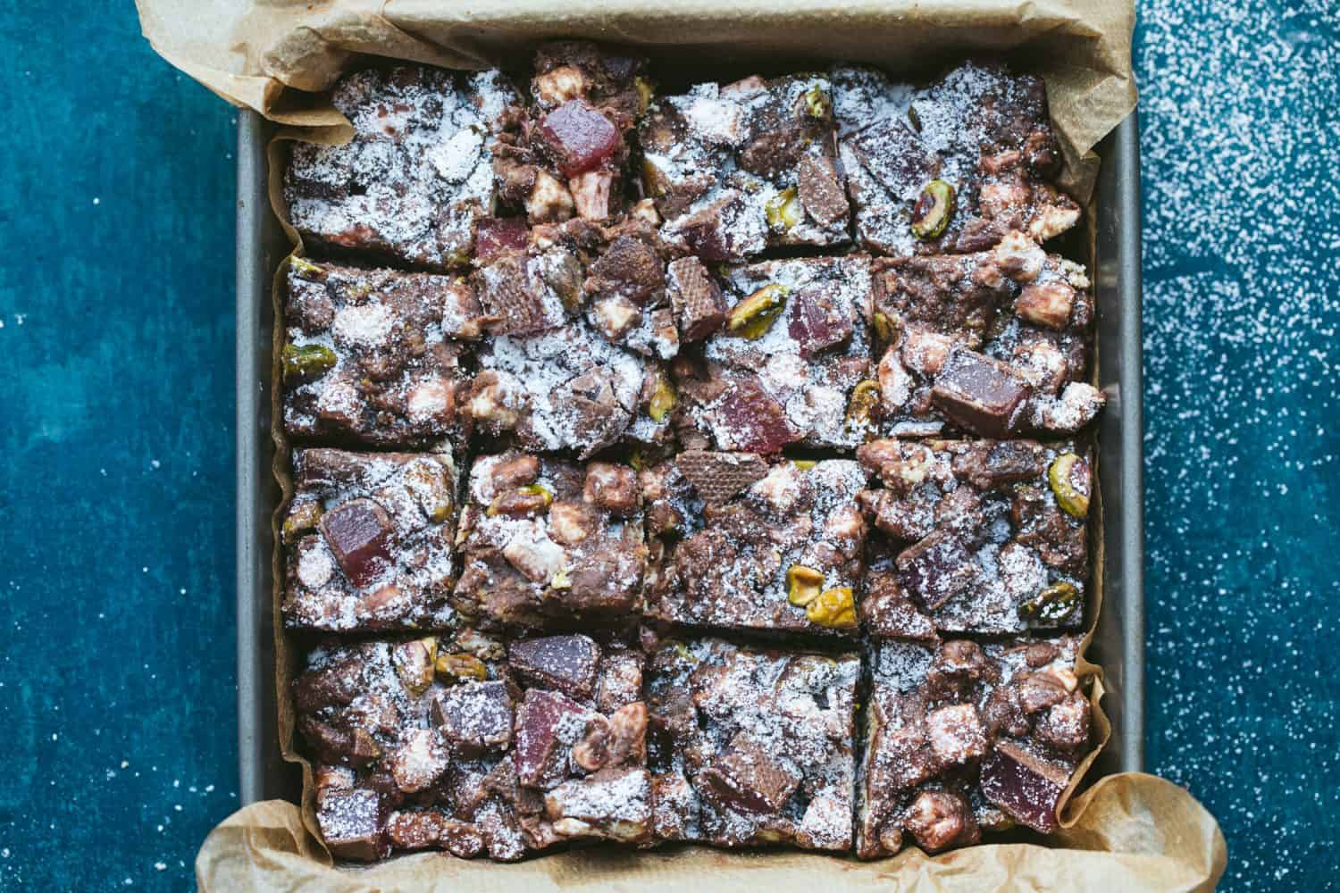 16 squares of chocolate Rocky Road in a baking tray lined with baking paper. 