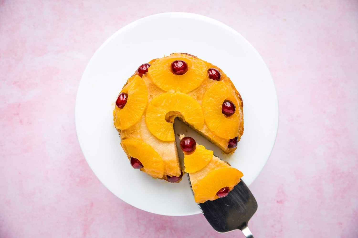 A pineapple upside down cake that has a slice cut out of it. 