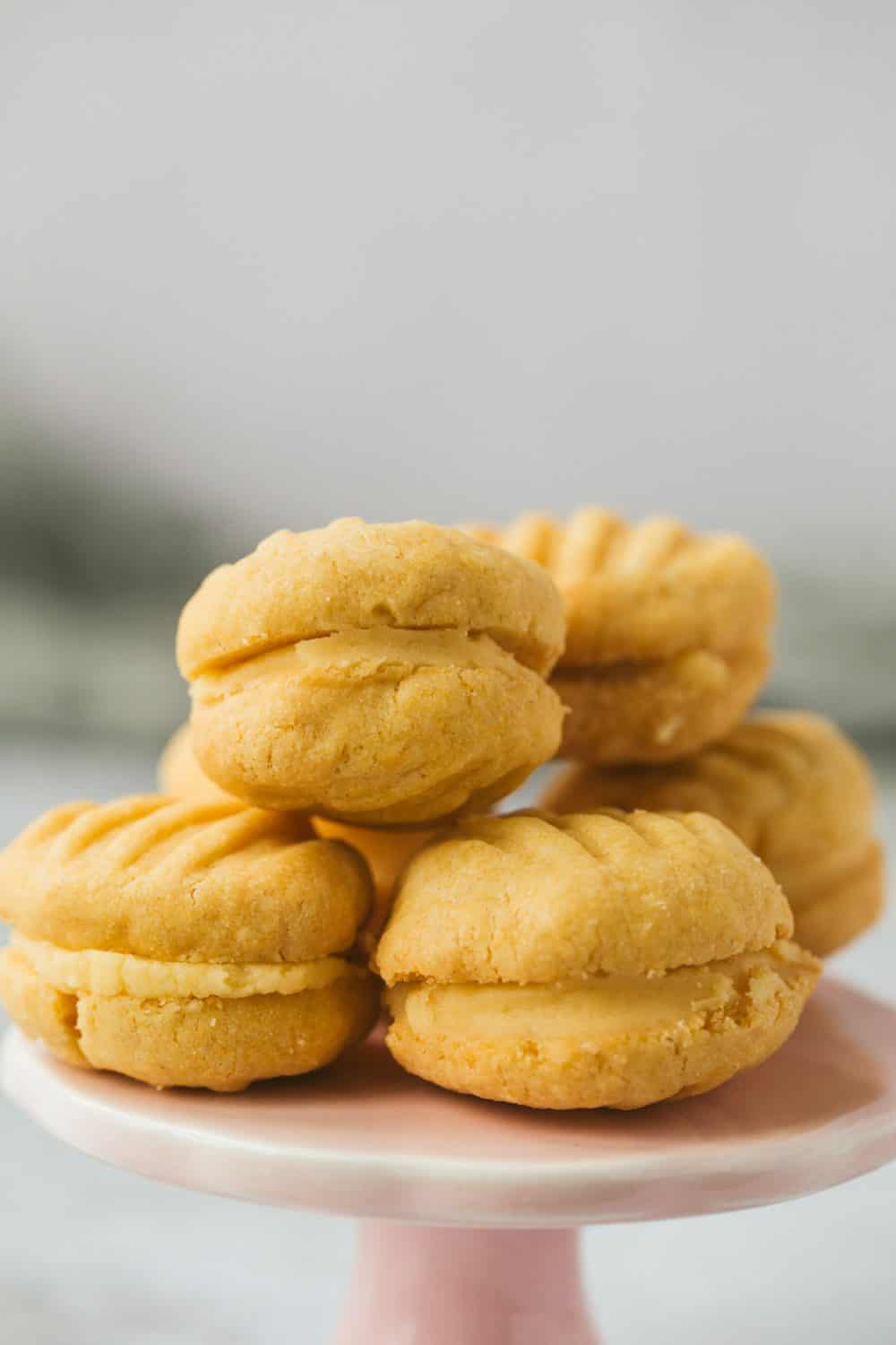 A stack of pale yellow cookies on a small pink stand.