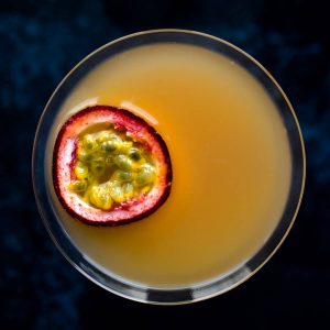 Overhead view of a pornstar martini with a slice of passionfruit floating on top.