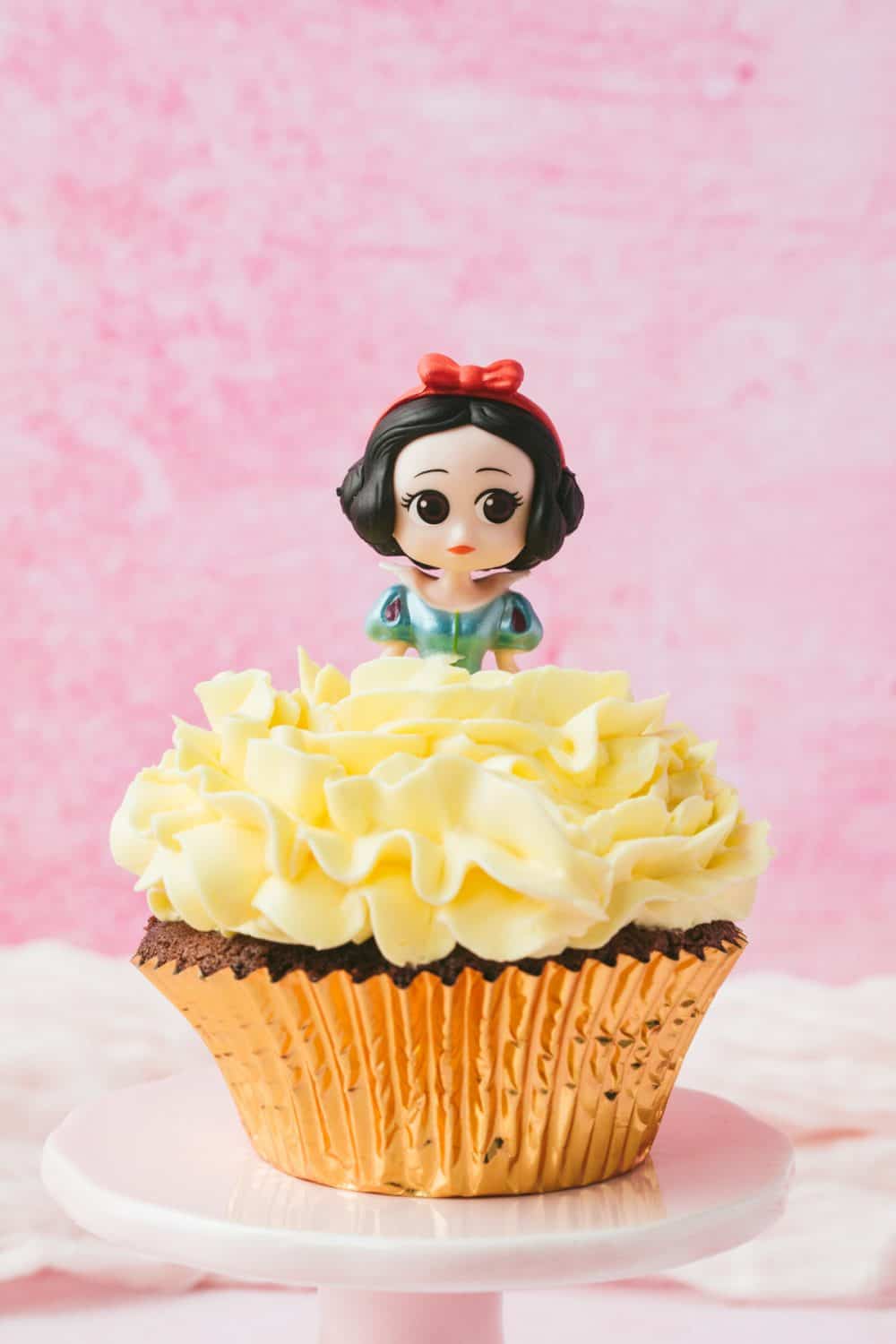 A snow white cupcake with yellow icing. 