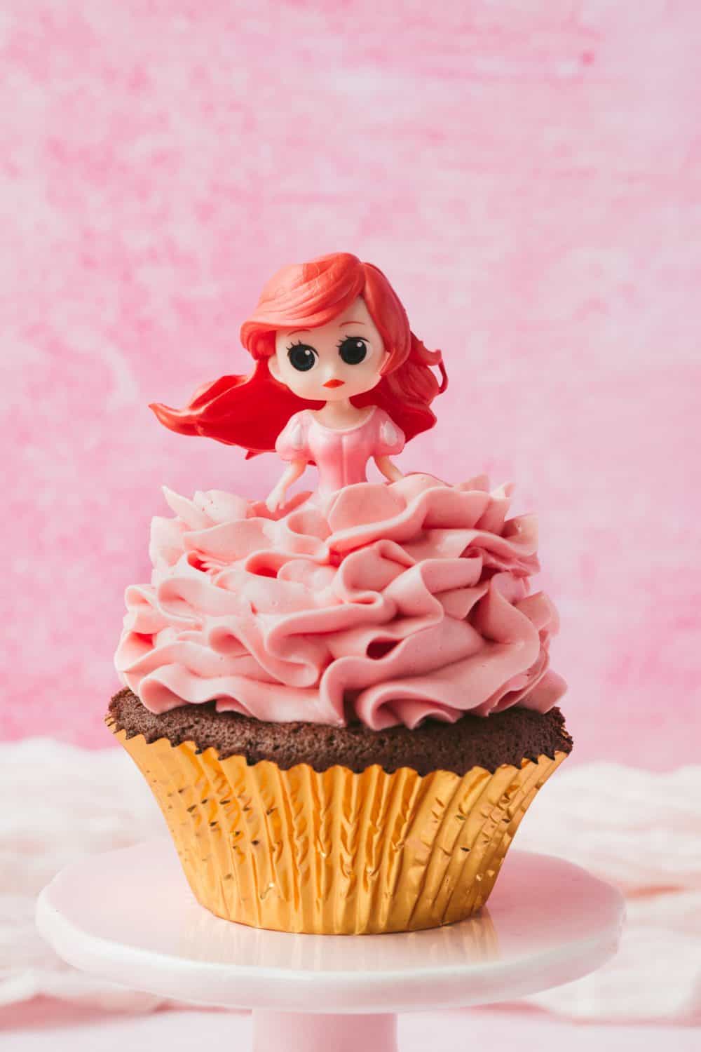 Disney princess Ariel on top of a chocolate cupcake covered in pink swiss meringue buttercream. 