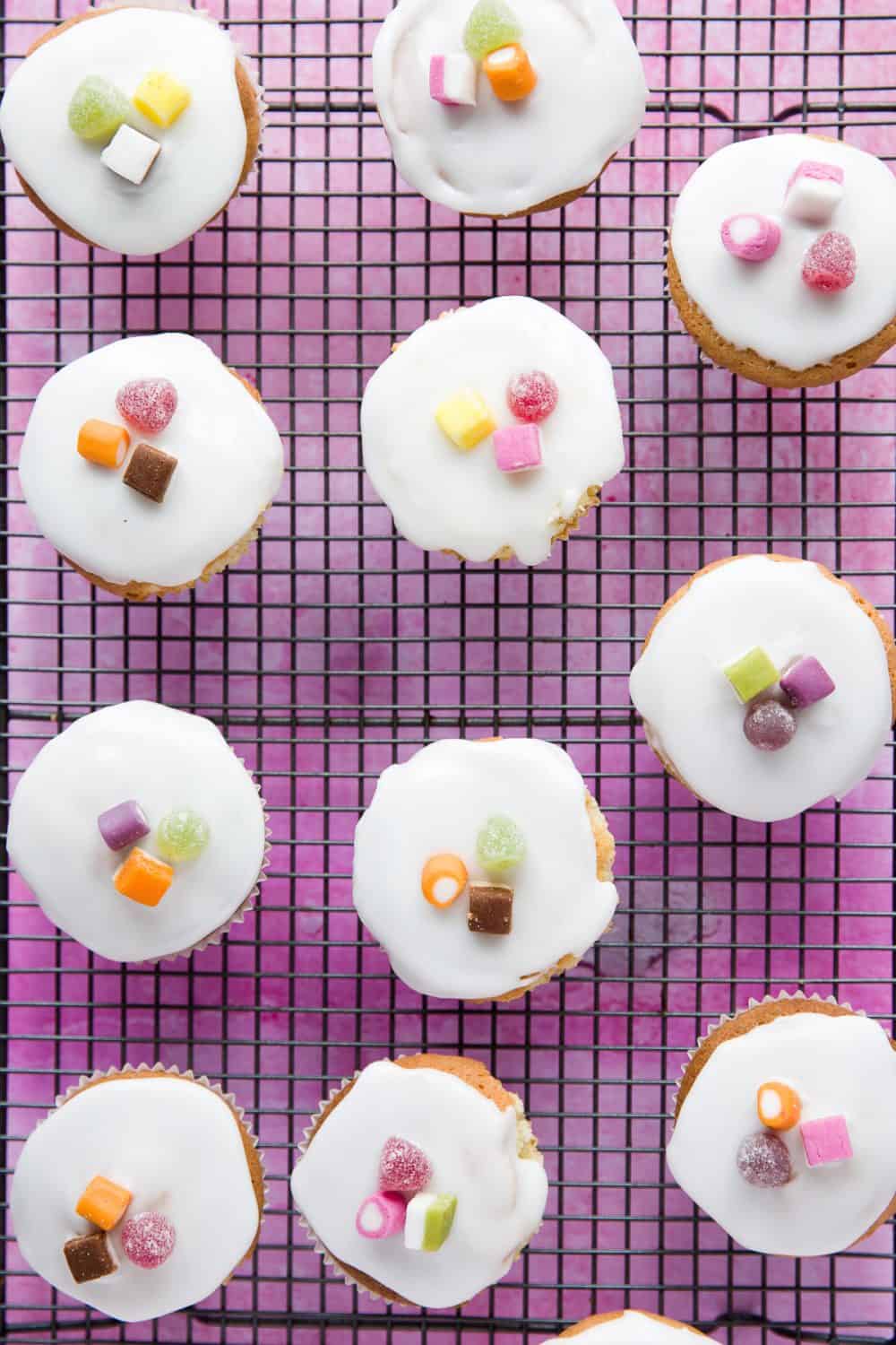 A cooling rack with fairy cakes on top of it. 