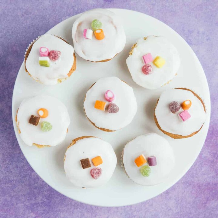 A white plate with 8 fairy cakes on top.