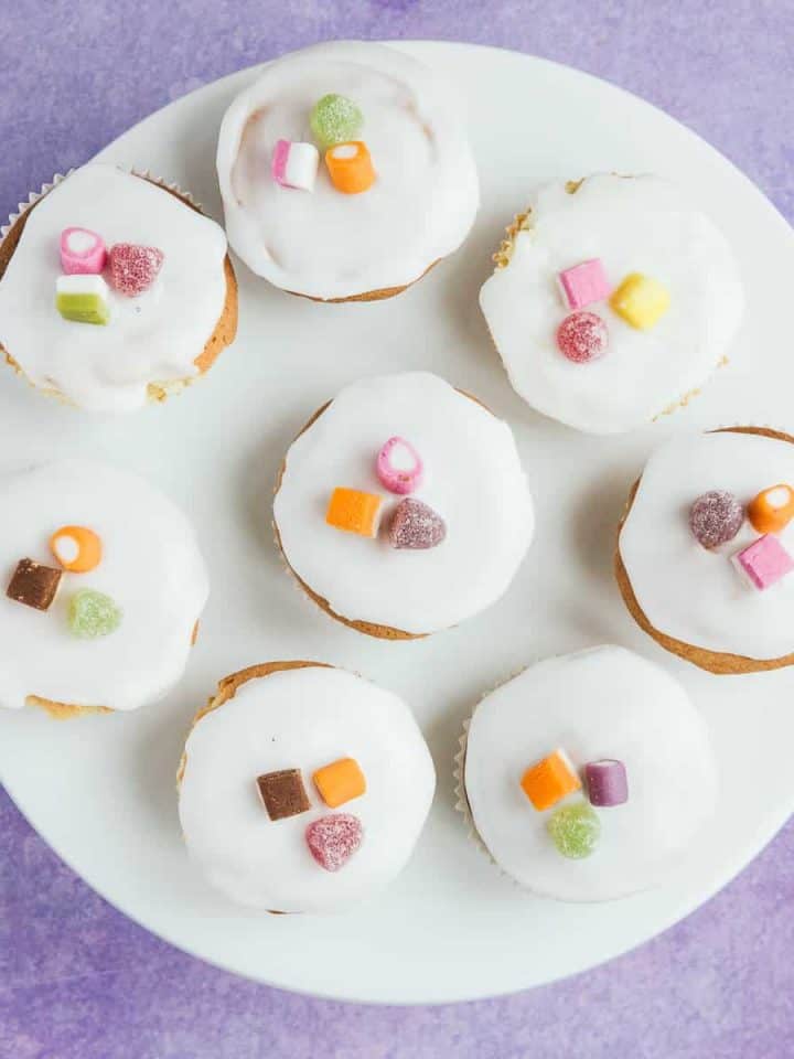A white plate with 8 fairy cakes on top.