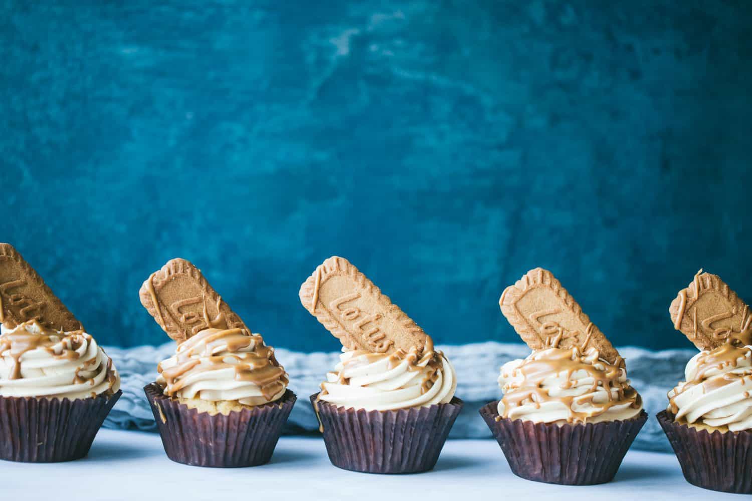 A row of five cupcakes in front of a dark blue background. 