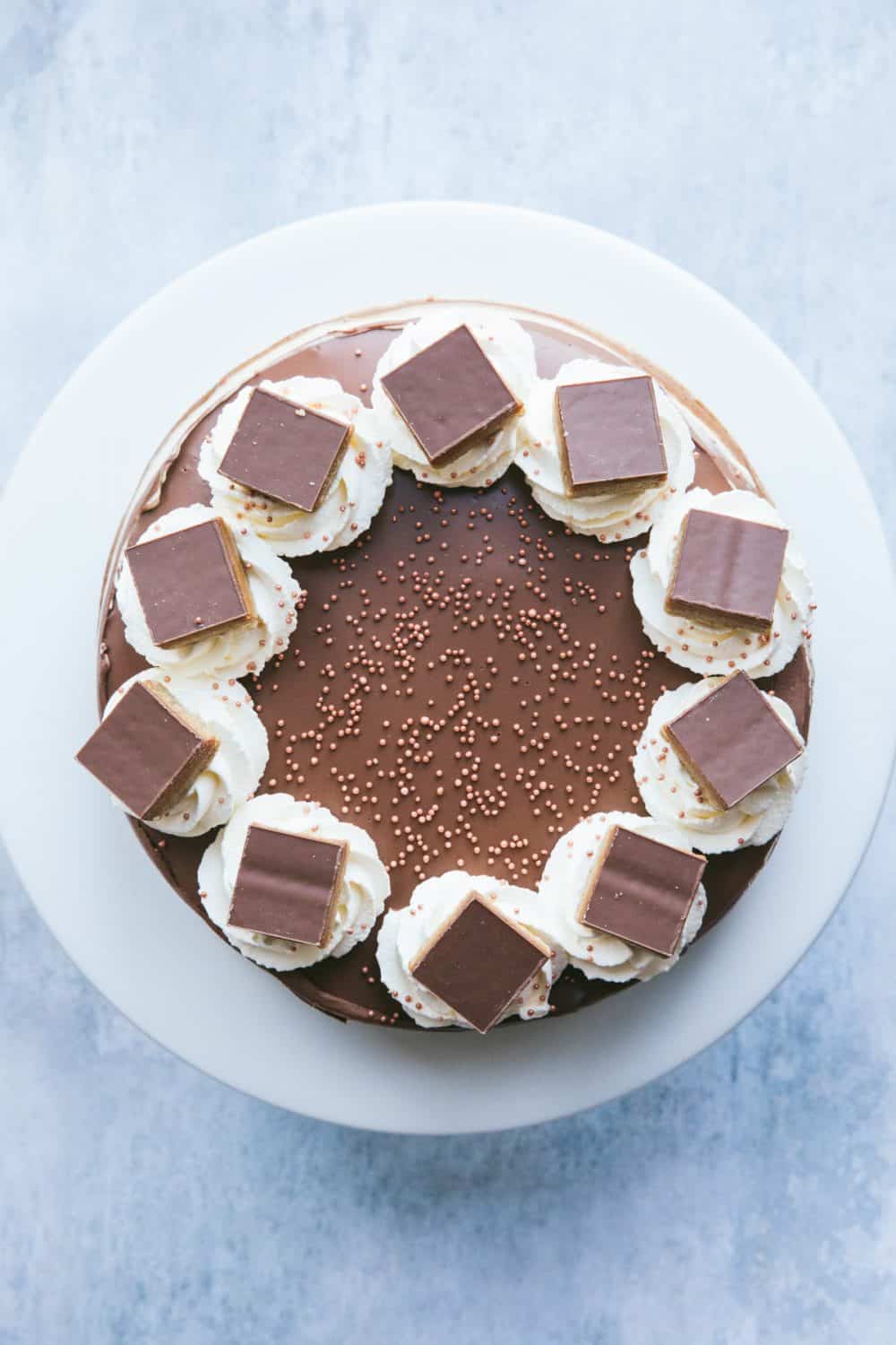 A Millionaire's Cheesecake with piped whipped cream and 10 individual squares of Millionaire's shortbread on top. 