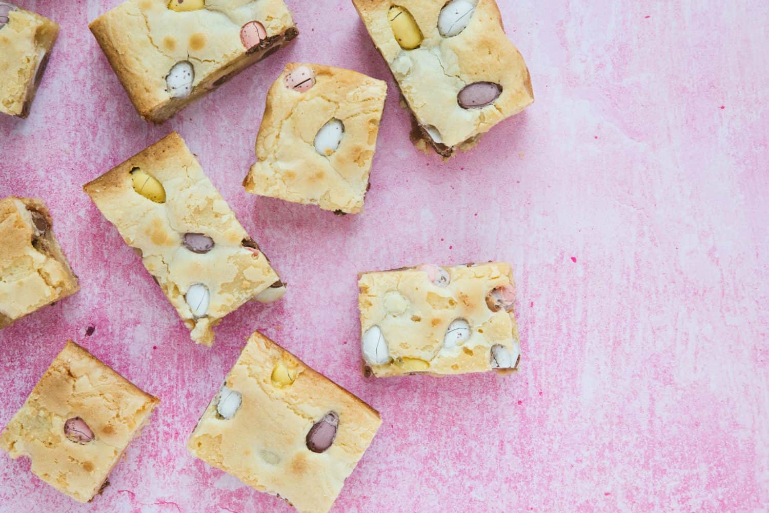 Slices of blondie on a pink background. 