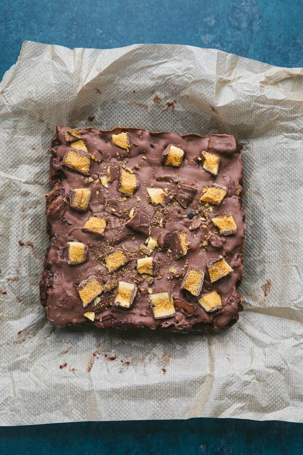 A slab of chocolate fridge cake on a piece of brown baking paper. 