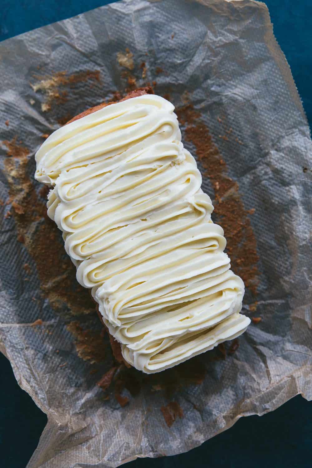 A loaf cake covered in swirls of white chocolate buttercream icing. 