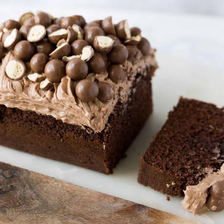 A Malteser loaf cake that has a slice cut out.