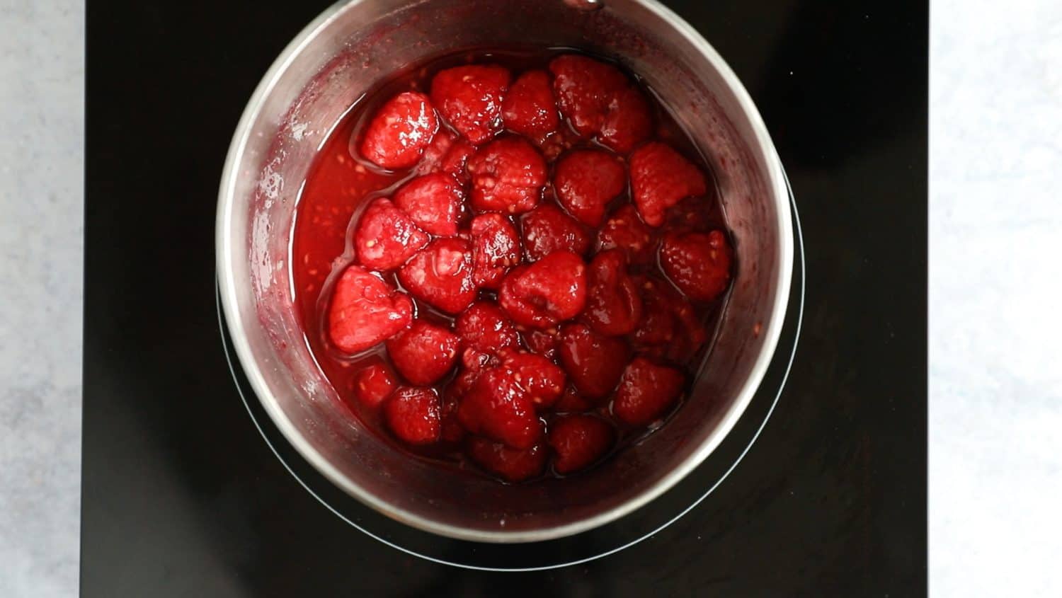 A saucepan with raspberries inside.