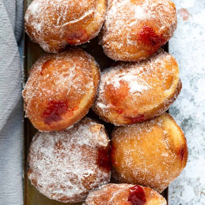 A tray of golden doughnuts filled with jam and coated in sugar.