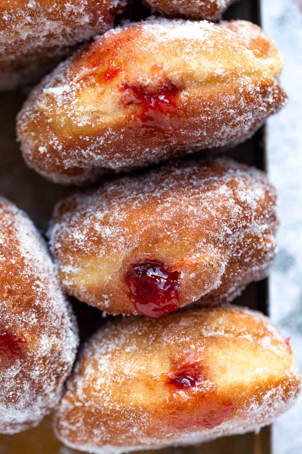 Golden homemade fresh doughnuts filled with strawberry jam. 