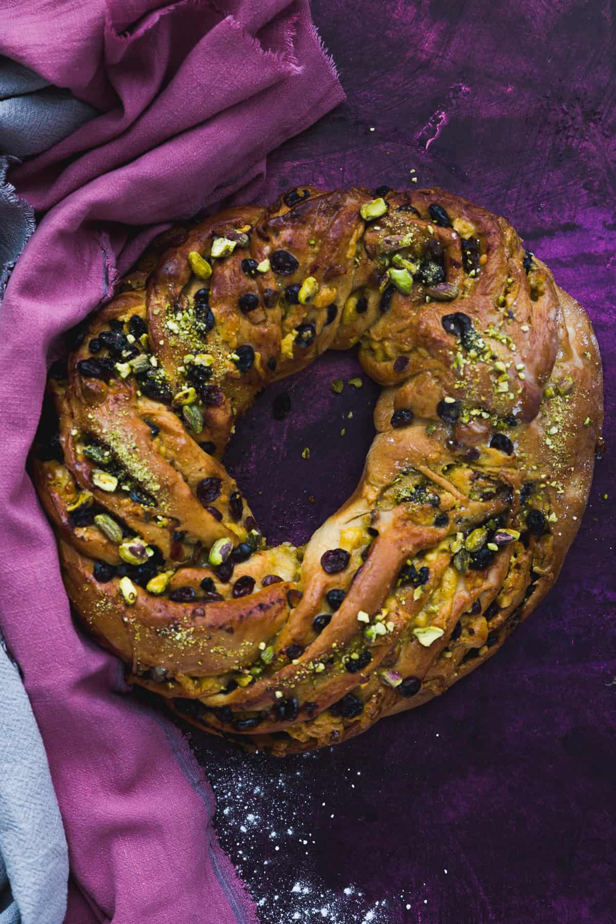 A close up image of a yeast risen bread filled with dried fruit and pistachio nuts. 