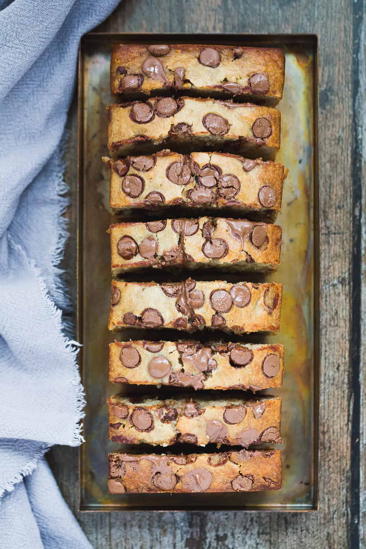 A banana bread with chocolate chips that has been sliced into 8 pieces and placed on a metal serving tray. 