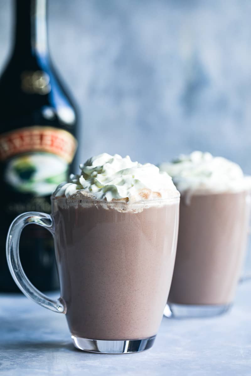 Two mugs of hot chocolate with squirty cream on top. 