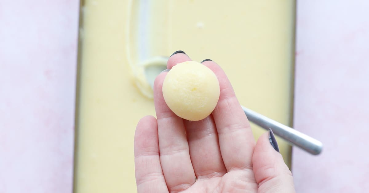 An open hand holding a ball of truffle mixture. 