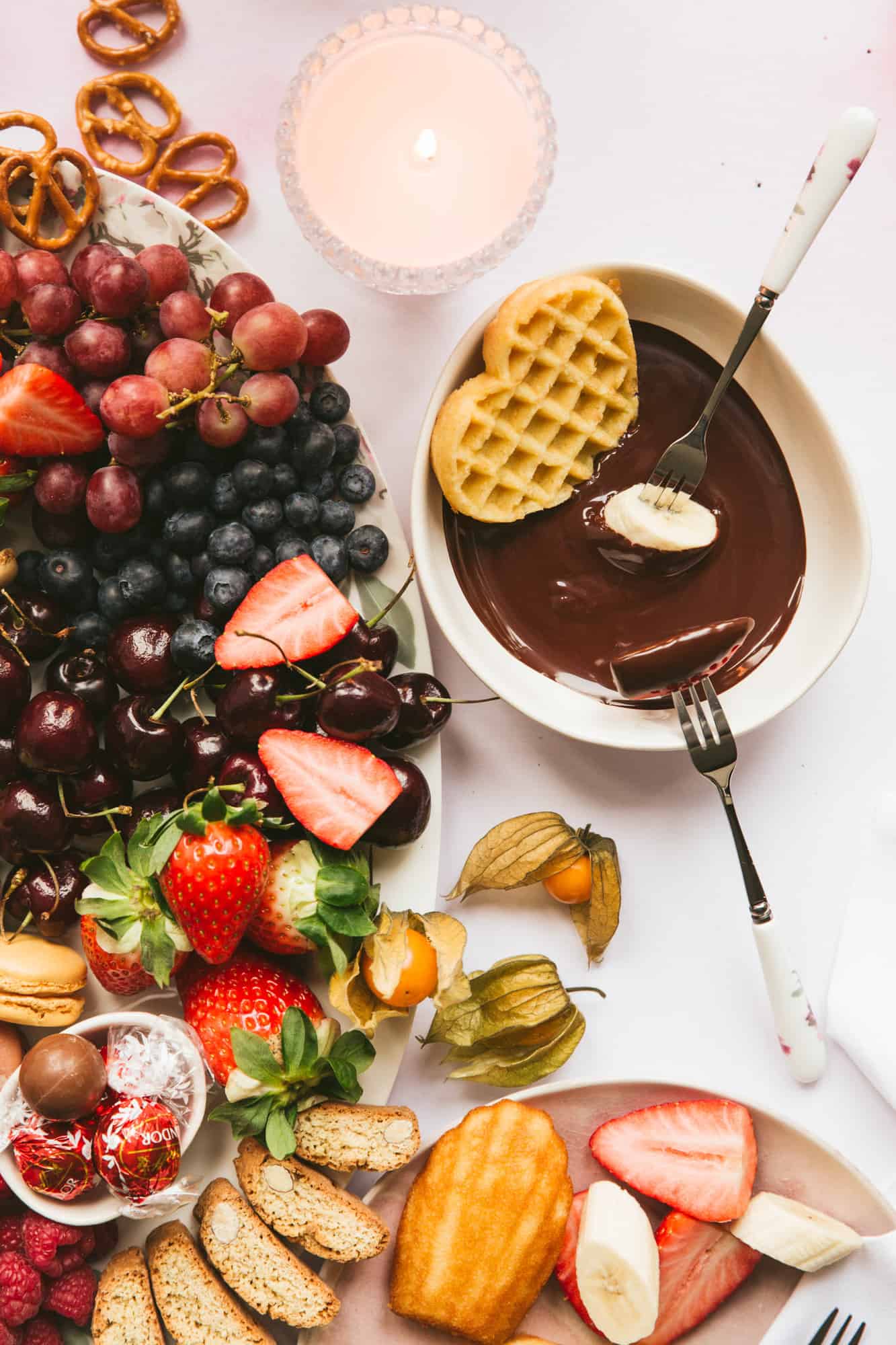 A chocolate fondue next to a large plate of fruit. 