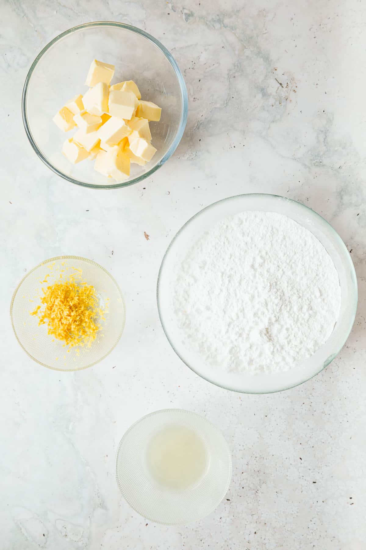The ingredients needed to make lemon buttercream: butter, icing sugar, lemon zest and lemon juice. 