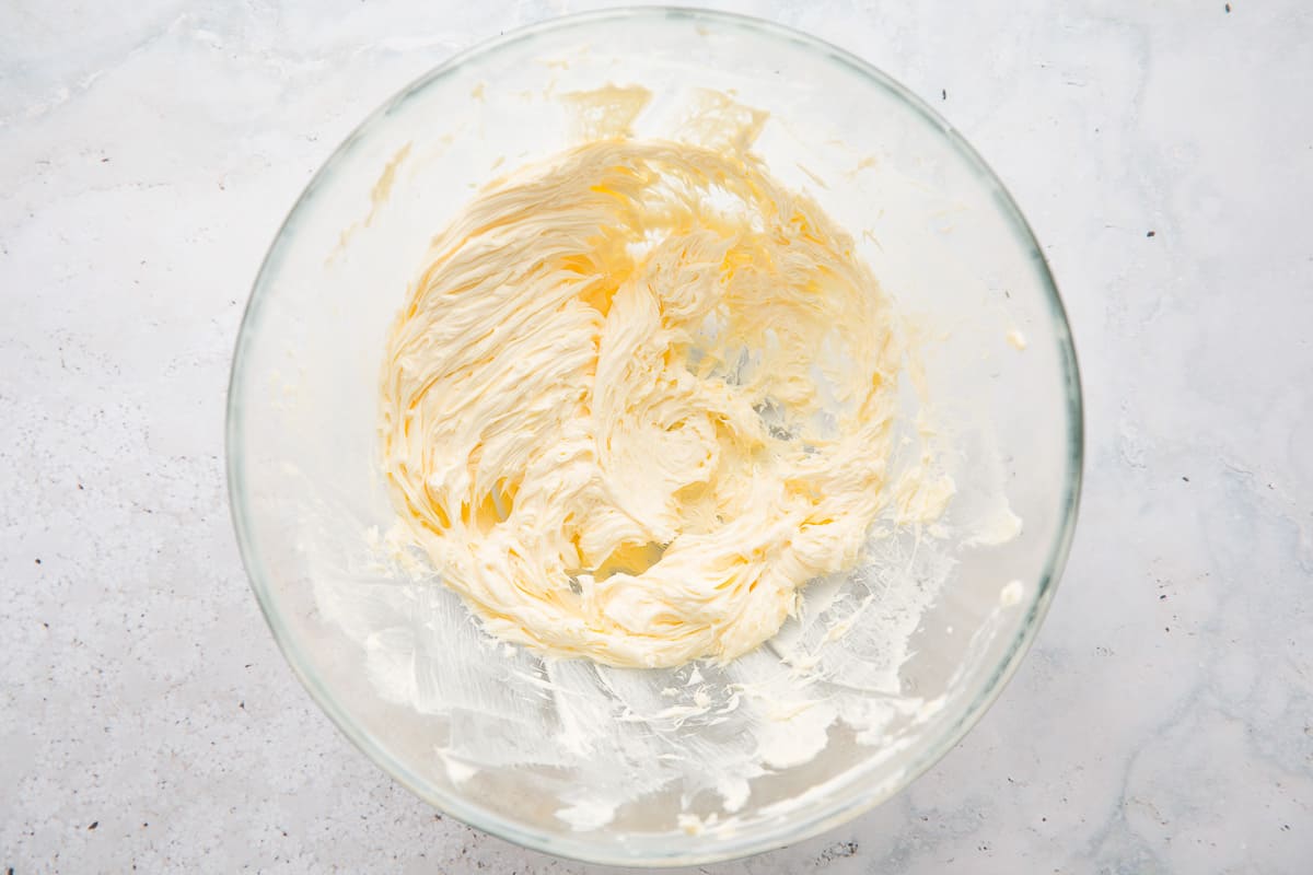 A large glass mixing bowl with soft butter. 