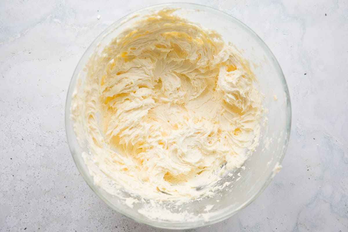 A large glass mixing bowl containing lemon icing. 