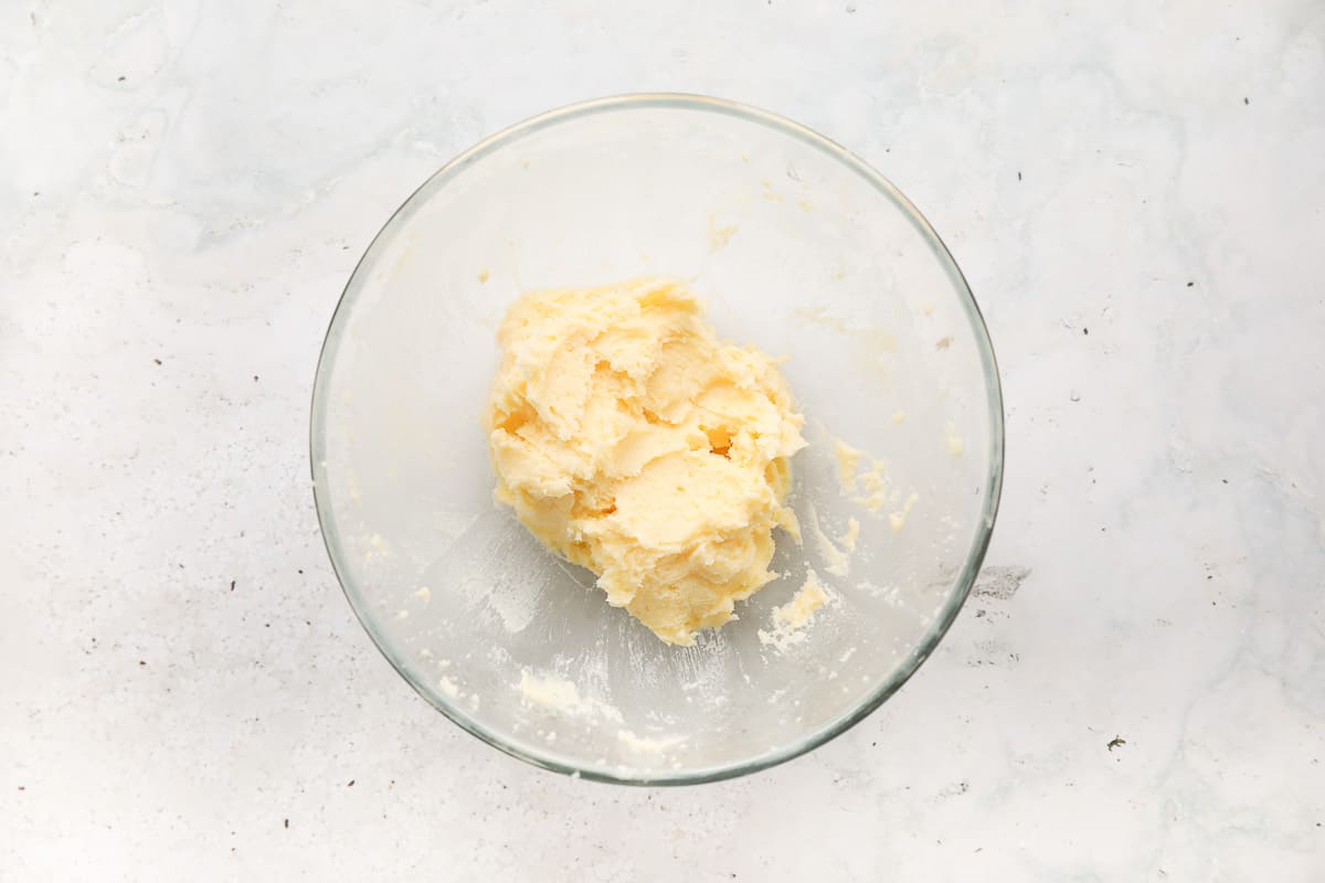 A glass mixing bowl containing butter and caster sugar that has been creamed together. 