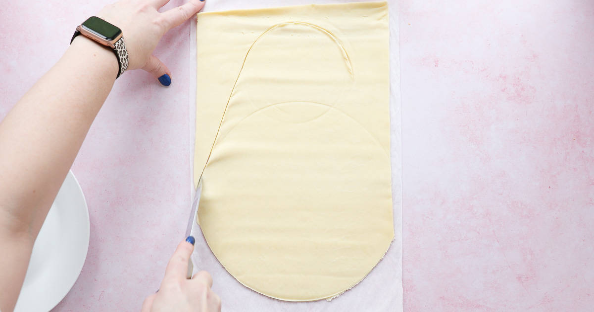 Cutting the shape of an Easter egg from a sheet of ready rolled shortcrust pastry. 