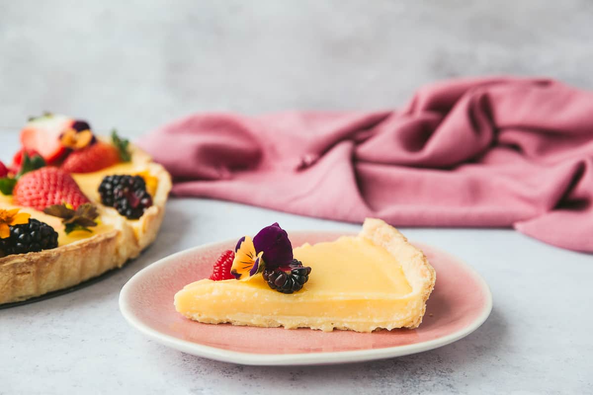 A slice of French lemon pie on a pink plate. 