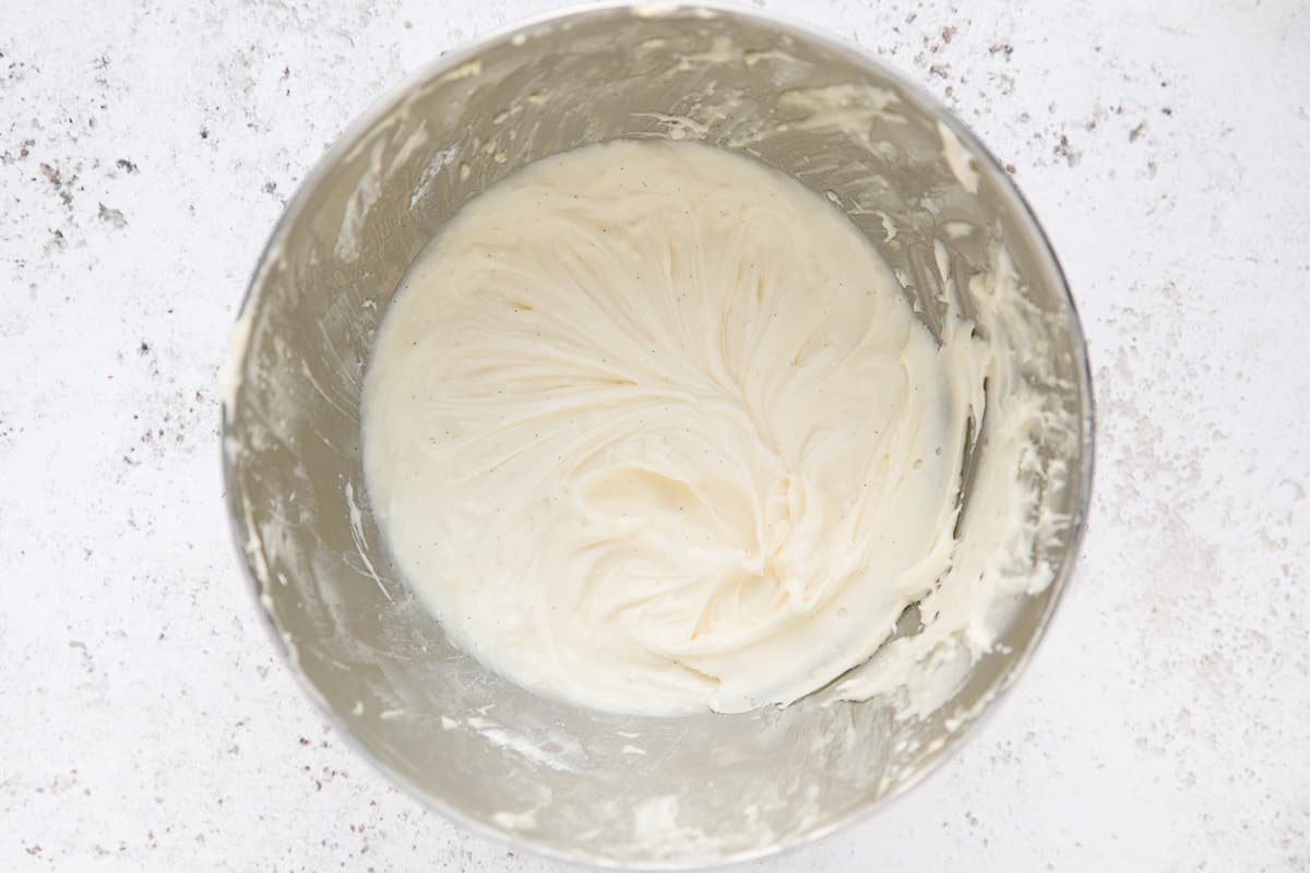 A bowl containing cream cheese frosting. 